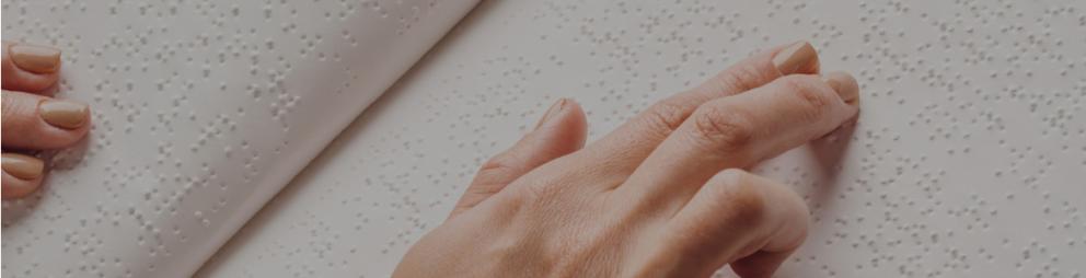 Banner universidad accesible Detalle de una mano durante la lectura de un libro en braille