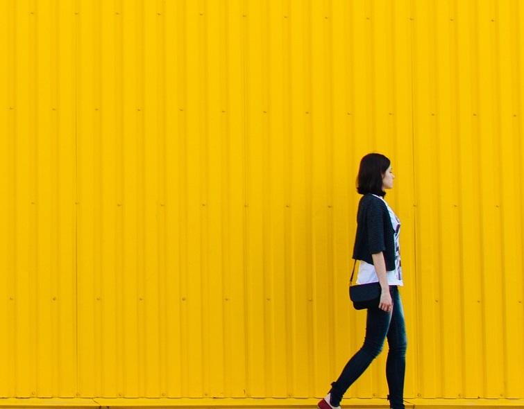 Mujer caminando sobre edificio amarillo
